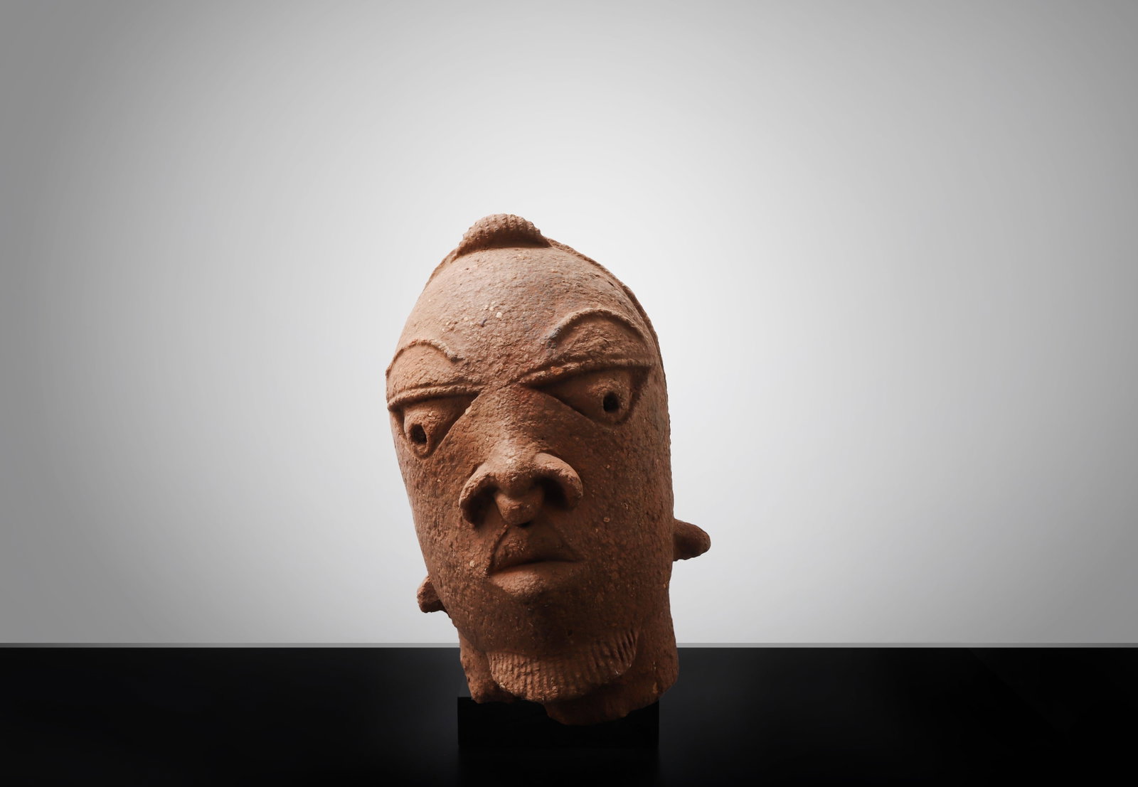 Nok Terracotta Head: Nigeria, Nok culture, possibly ca. 500 BCE - 200 CE. A large terracotta head modeled in reddish-brown earthenware, with strongly stylized facial features including deeply set almond-shaped eyes with p