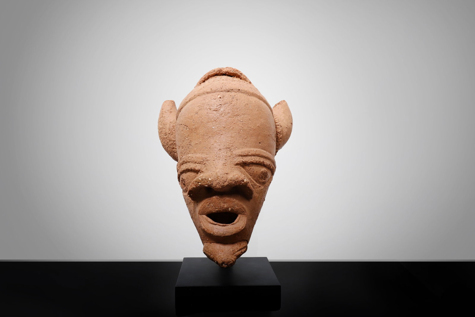 Large Nok Terracotta Horned Head, Nigeria, 500 BCE - 200 CE: West Africa, Nigeria, Nok culture, circa 500 BCE?200 CE. A large and impressive authentic Nok terracotta head, modeled in elongated oval form with highly expressive stylized features. The face is defi