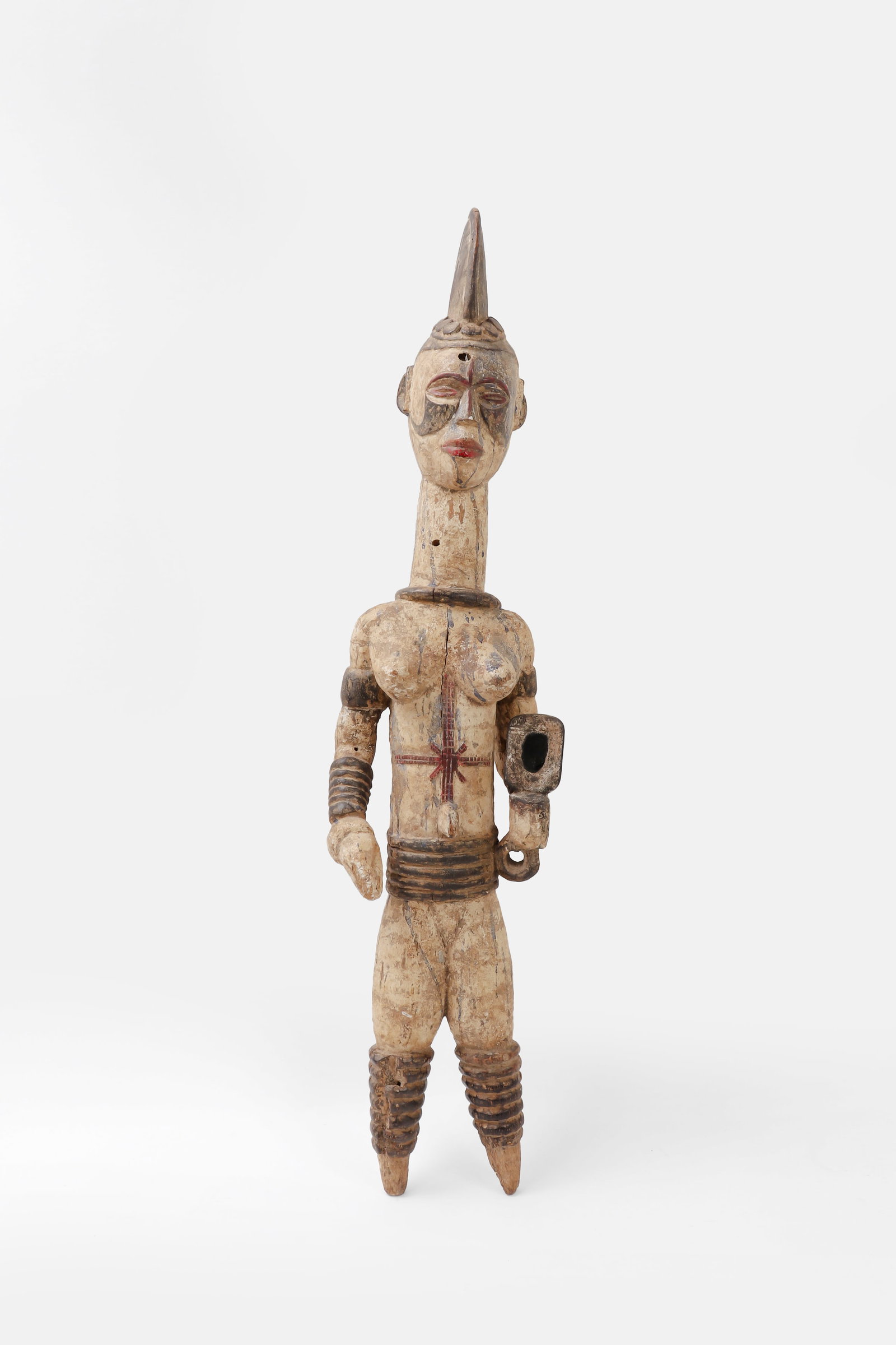 Igbo Alusi Carved Wood Figure: Nigeria, Igbo culture, 20th century. Carved wood Alusi figure shown standing with elongated body, high crested coiffure, articulated arms, and pointed legs. The face is strongly modeled with almond-sh