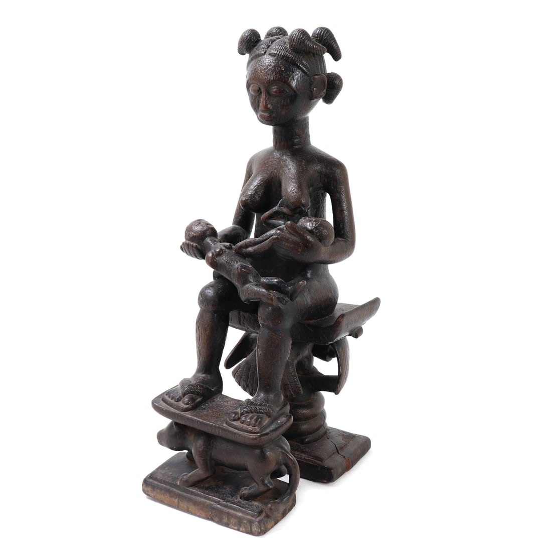 Yoruba Maternity Figure on Throne: Yoruba people, Nigeria, 20th century. A carved wood seated female maternity figure, shown enthroned and holding twin children across her lap. The figure is depicted with rounded facial features, promi
