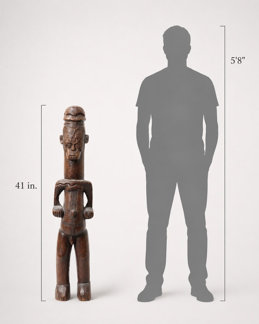 Large Igbo Male Shrine Figure, Nigeria: Nigeria, Igbo peoples, mid-20th century. Large carved wood male figure with elongated columnar body, squared arms, bent legs, and stylized facial features beneath a tall coiffure or cap-like