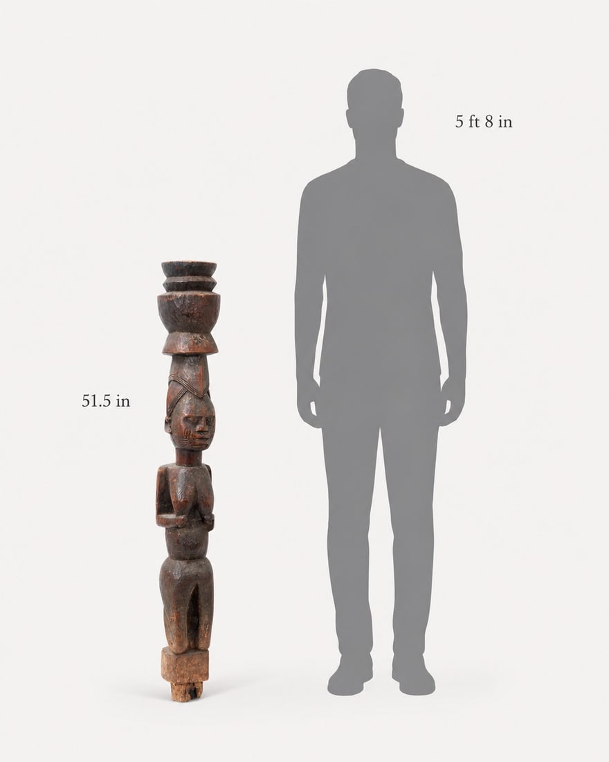 Large African Carved Wood Female House Post: Africa, carved wood figural house post depicting a standing female figure with stylized facial features, bent arms, and a tiered vessel-form finial above the head. The surface shows a dark brown patin