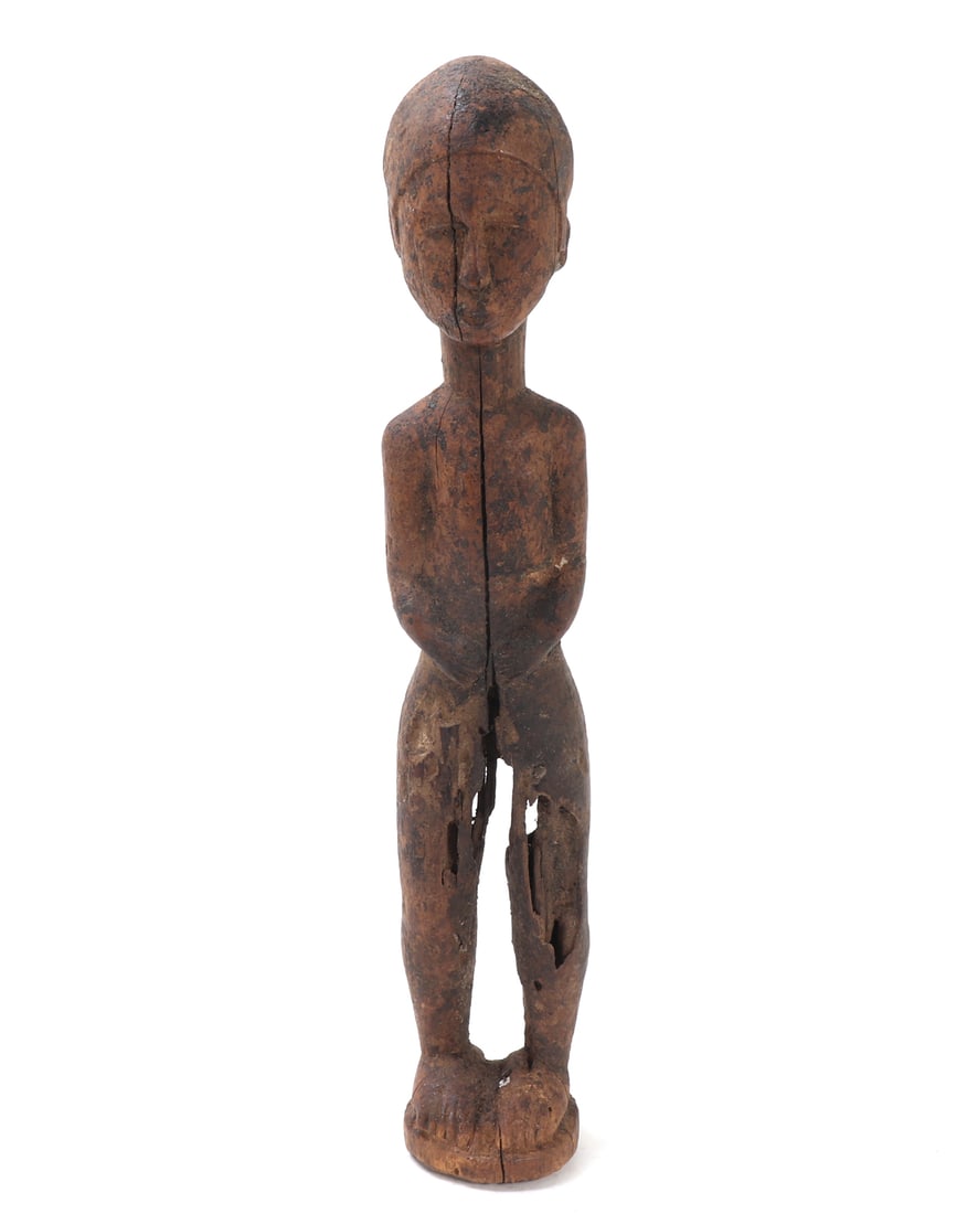 African Wood Carved Guardian Figure: Unique minimalistic carved African wood statue of a standing guardian figure. Depicted standing with arms in front, hands clasped in front. Size 11 5/8" H x 2" W Collected prior to 2008, ex-Lacy Galle