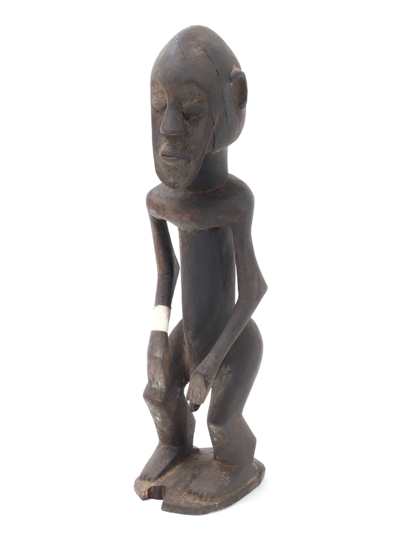 African Wood Carved Guardian Statue: Handsome early wood carved African male guardian statue. Carved from a single piece of light wood, he is depicted standing nude in a crouched form. Bulbous eyes with protruding lips and nose. Arms res
