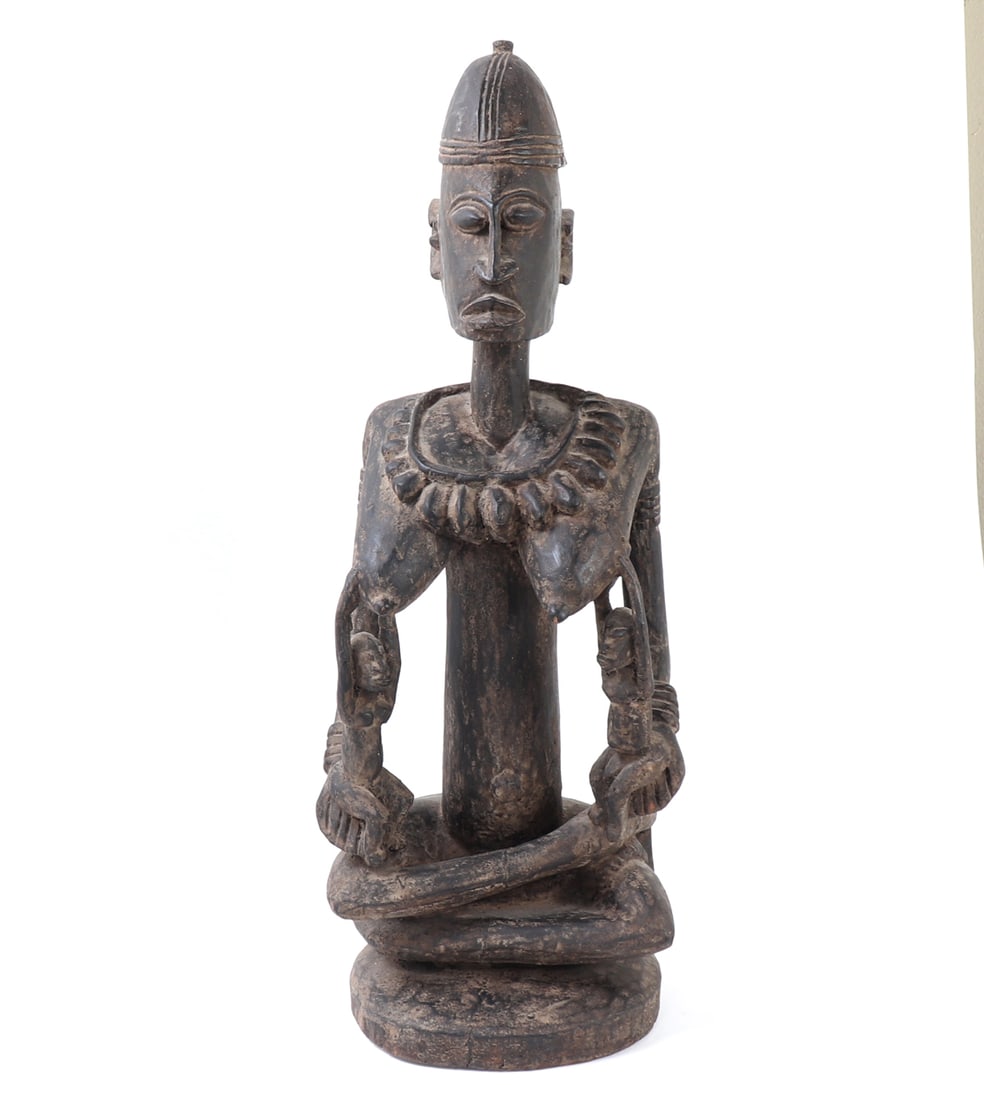 African Maternity Figure with Children: African carved wood maternity figure, possibly West African, depicting a seated female figure with elongated neck, domed coiffure, and stylized facial features. The figure is shown seated on a circula