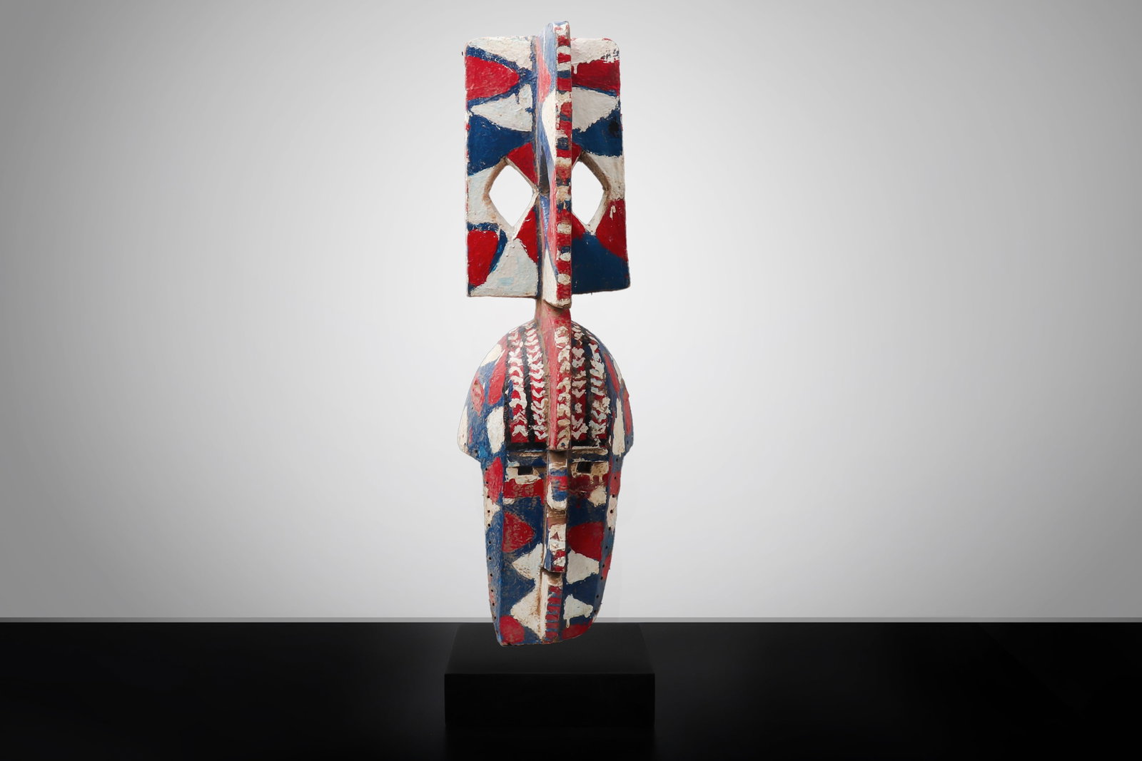 Bobo Polychrome Plank Mask, Burkina Faso: Burkina Faso or Mali, Bobo Peoples, 20th Century Carved wood plank mask of vertical form, with a rectangular openwork crest above a domed helmet and elongated facial section. The surface painted in re