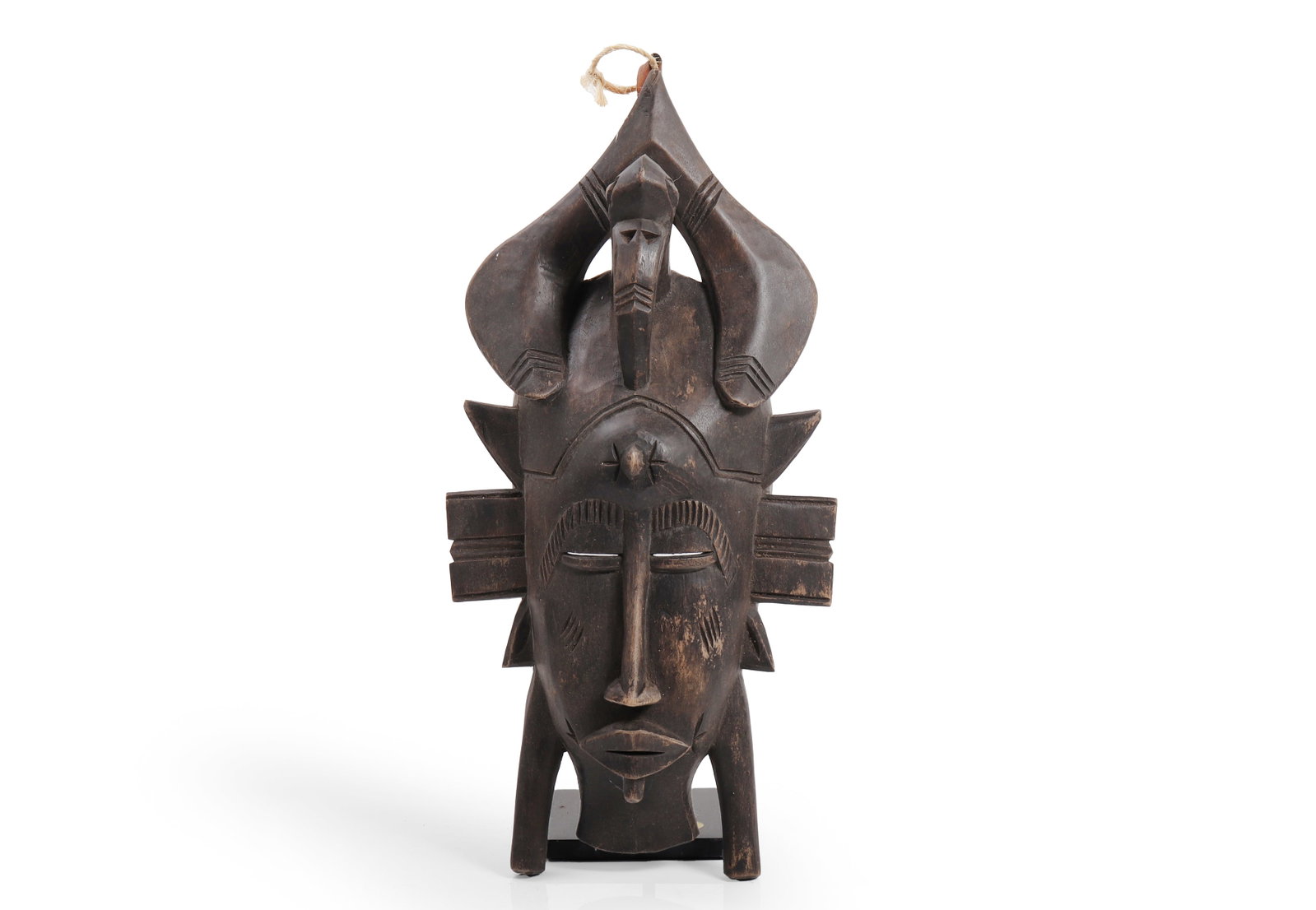 Senufo Carved Wood Kpelie Mask: Ivory Coast, Senufo people. Carved wood kpelie mask of refined vertical form, with downcast slit eyes beneath arched brows, a long straight nose, and a small pursed mouth, surmounted by a seated horne