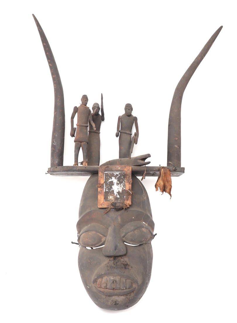 Great Horned Fon Mask w/ Figures: African wood carved mask of the Fon peoples with a large toothed face and pierced to the under side of the eyes. The forehead with a blackened mirror and horned headdress featuring three village