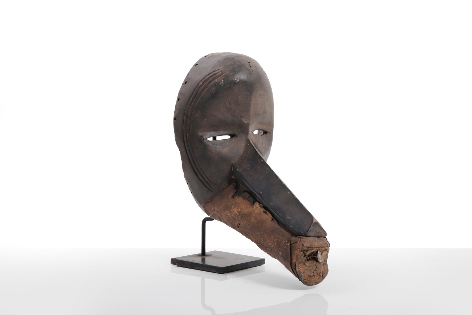 West African Beaked Mask, labeled Dan Kono: Probably West Africa, 20th century or earlier. Carved wood mask of deep rounded form with narrow slit eyes and a long projecting beak-like nose or snout, the perimeter pierced for attachment of fiber