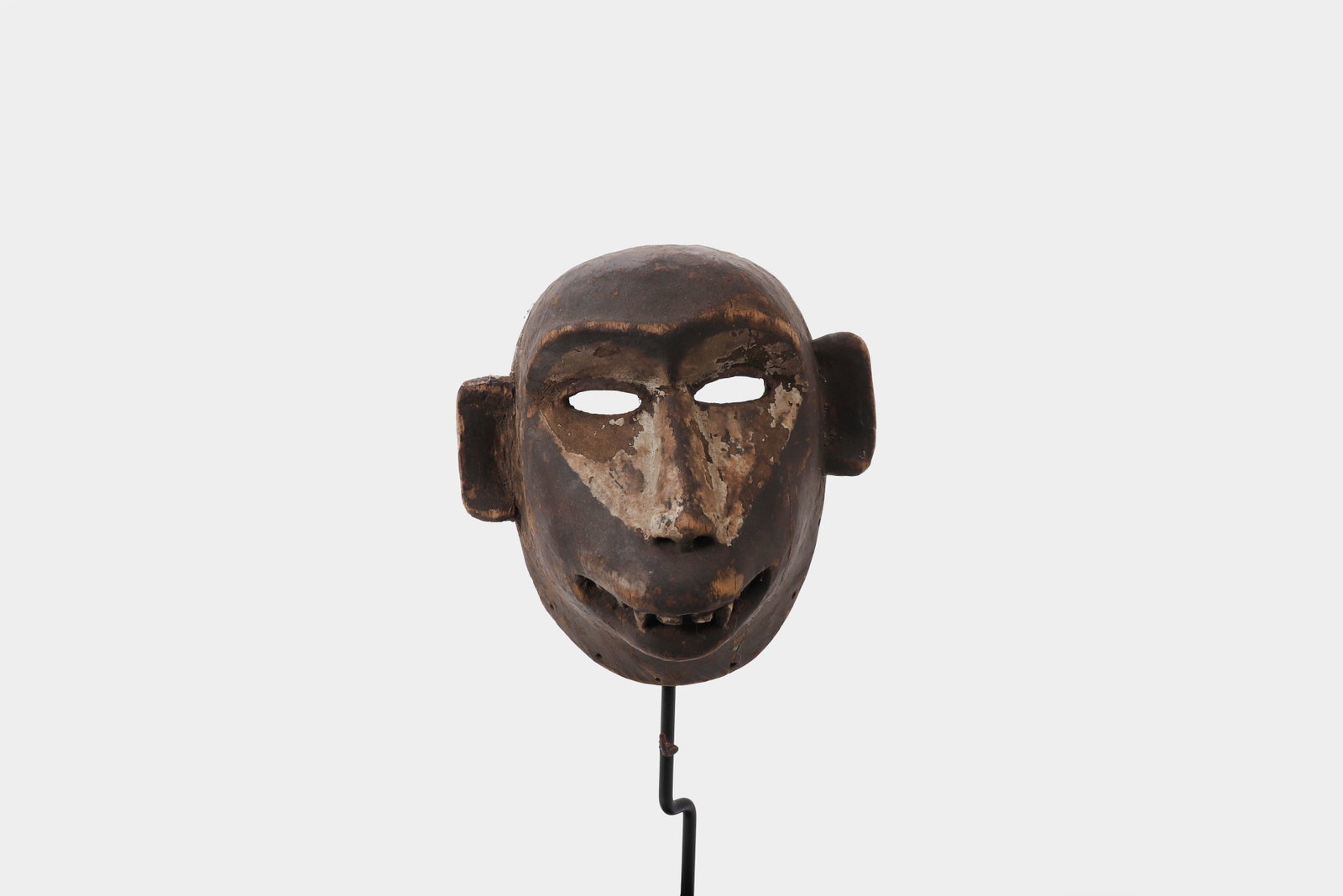 Bulu Zoomorphic Tribal Mask: Central Africa Late 19th - Early 20th Century Bulu peoples. A carved wooden mask of compact, rounded form, the face rendered with simplified features including almond-shaped pierced eyes, a broad