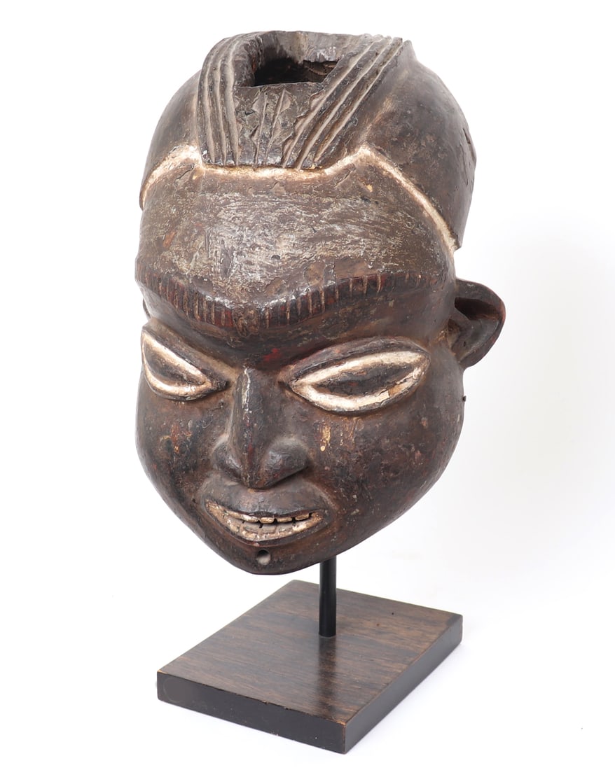 Bamum Helmet Mask, Cameroon: Central Africa, Cameroon, Kingdom of Bamum 1394-1916. Bamum peoples painted helmet mask. Dark patina with kaolin highlighted eyes, teeth and hairline. Size 14" H x 11 1/2" W x 12" L, custom stand