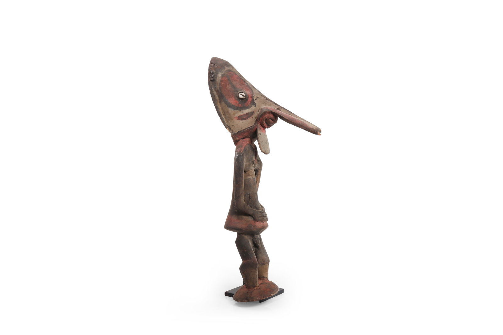 Papua New Guinea Carved Bird-Head Male Figure: Papua New Guinea, circa 1980. Carved and painted wood standing figure with attenuated body and dramatic bird-form head, the elongated beak projecting forward above a single shell-inset eye and