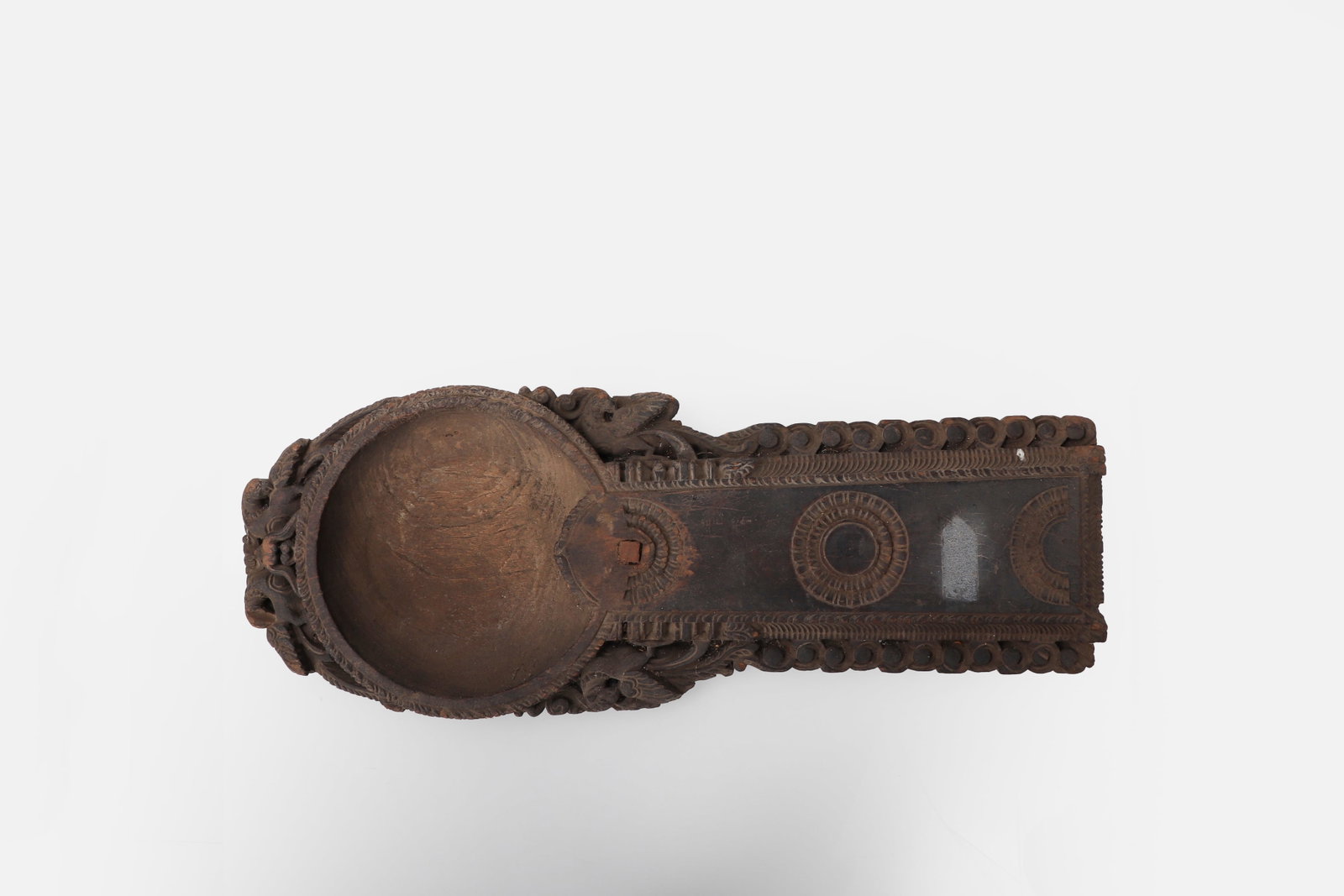 Indian Carved Paathra Chirava: South India, Kerala, 19th / early 20th century. Carved wooden paathra chirava, or coconut-scraping bowl, of elongated form with an integral circular basin and extended handle-like platform. The