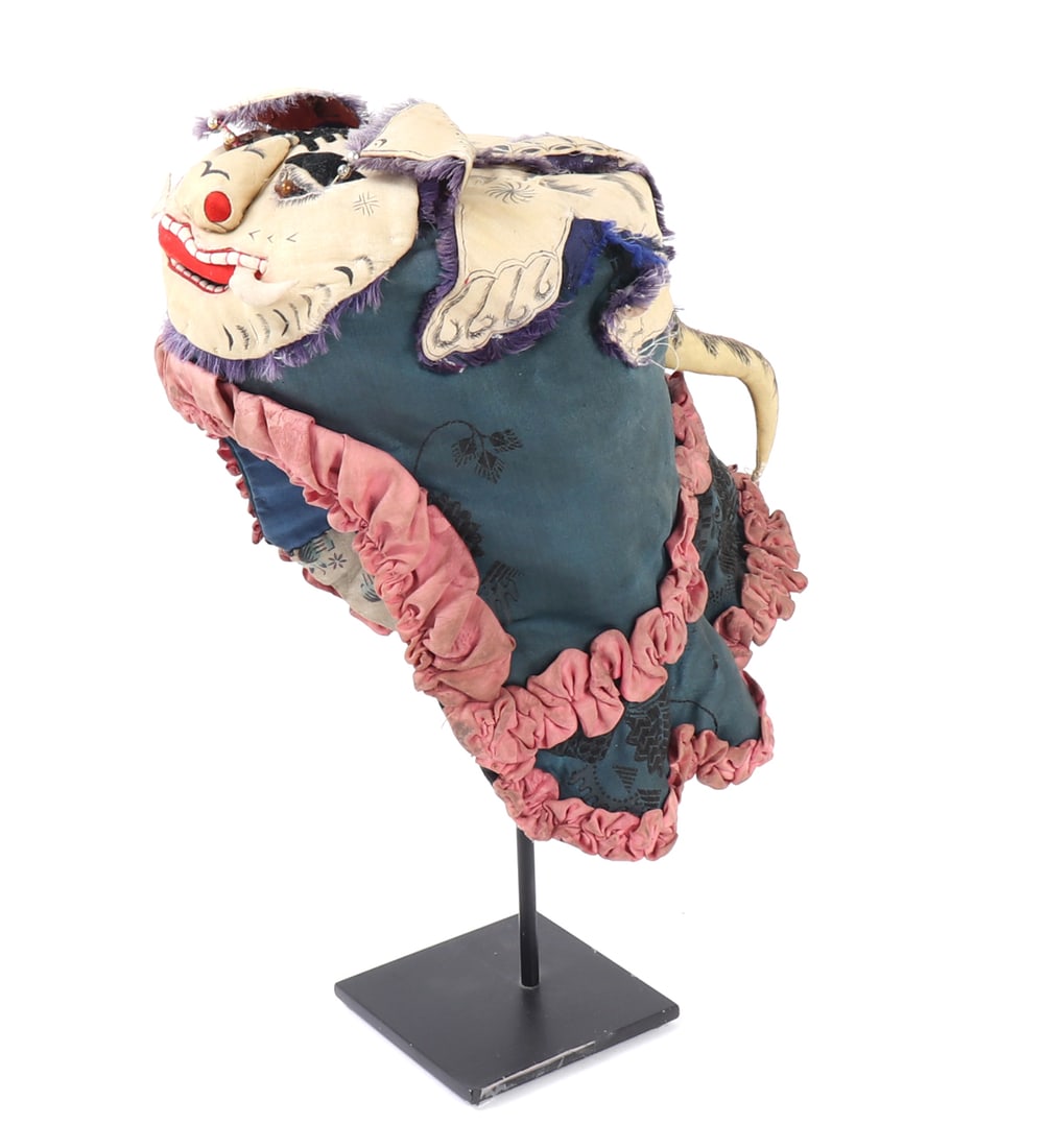 Chinese Child's Tiger-Form Protective Hat: China, late 19th to early 20th century. Traditional child's protective hat in the form of a stylized tiger or mythical beast, with painted and applied facial features above a blue-green textile cap ed