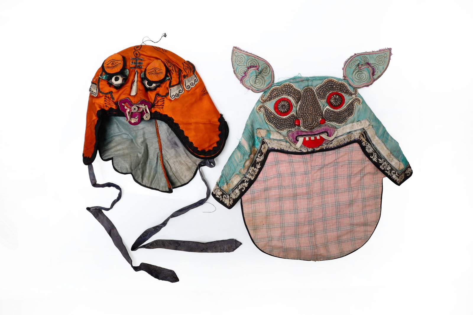 Set of Antique Chinese Baby Hats: This charming pair of antique Chinese baby hats showcase the vibrant colors and symbolic artistry traditionally used in children's garments. One hat features a bright orange body framed by a bold