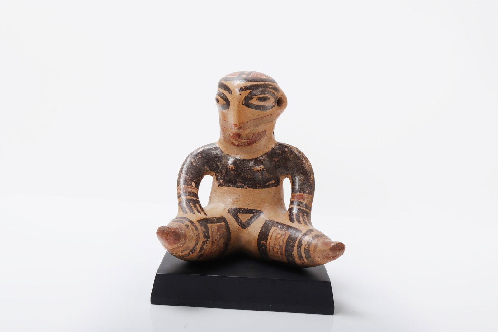 Pre-Columbian Polychrome Nicoya Seated Female, Costa Rica 600 - 800CE: A rare and highly expressive ceramic figure depicting a seated female with splayed legs and arms resting upon the thighs, the form rendered with a striking combination of volumetric modeling and