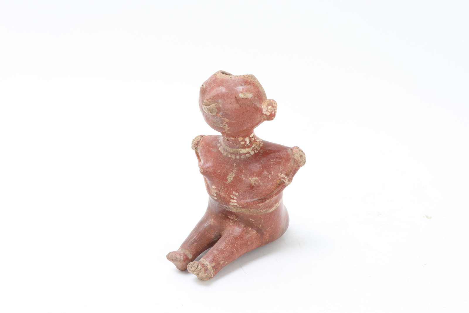 Pre-Columbian Seated Female Figure: Pre-Columbian, West Mexico, Nayarit, Chinesco Type, circa 300 BCE - 300 CE Pottery seated female figure of Chinesco type, shown with elongated legs extended before the body and arms folded tightly