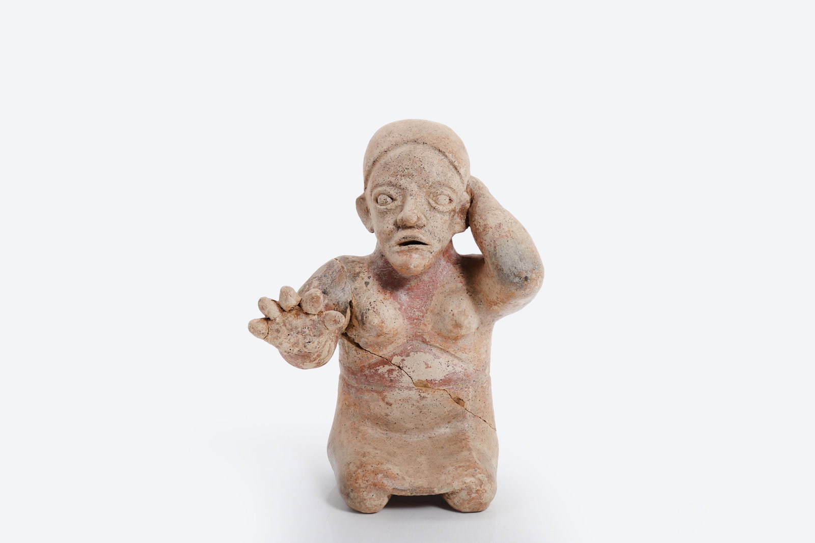 West Mexican Colima Terracotta Seated Female Figure: West Mexico, Colima Culture Protoclassic to Early Classic Period, circa 100 BCE - 300 CE A hollow-molded terracotta female figure depicted in a kneeling or seated posture, the right hand raised to
