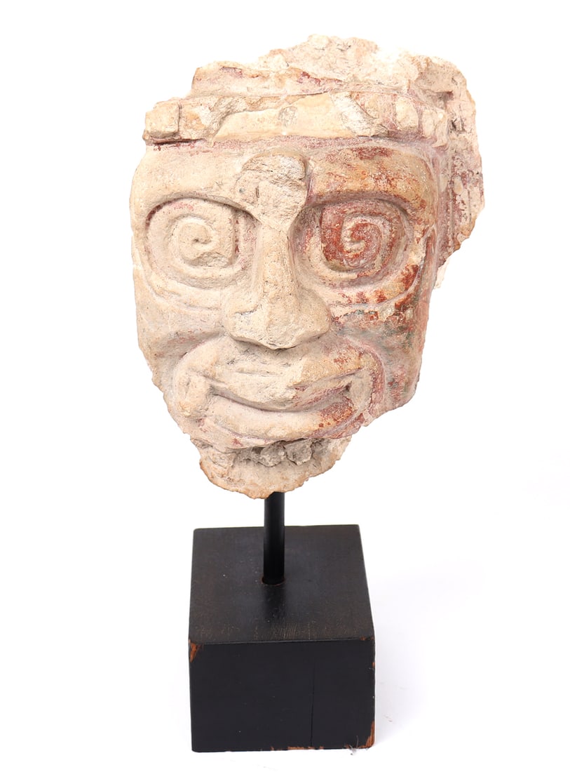 Maya Stucco Deity Head, Possibly Chaac: Pre-Columbian, Maya region, Southern Mexico or Guatemala, Classic Period, circa 600 - 900 CE. Stucco architectural fragment modeled as the head of a deity, the face with prominent spiral eyes, broad