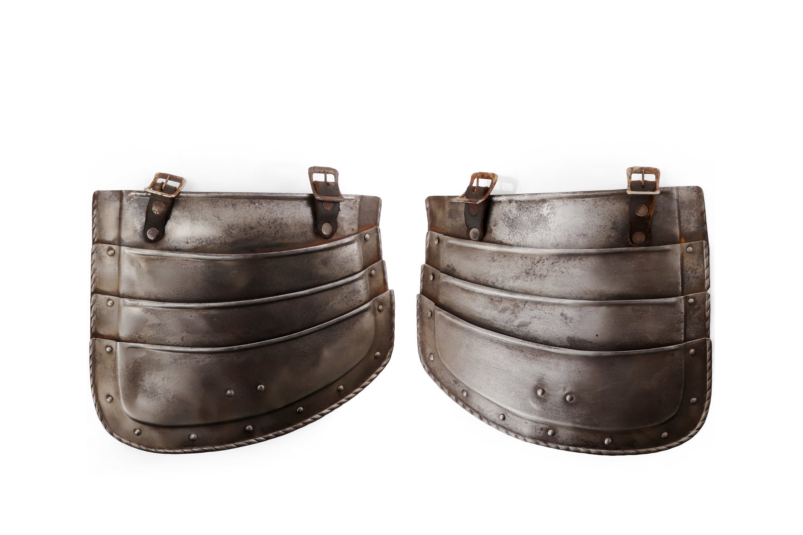 European Steel Tassets, 16 C. Style: European, in the 16th century style. Pair of steel tassets, each formed with four articulated horizontal lames, riveted side plates, leather suspension straps, and small buckle fittings. The lower