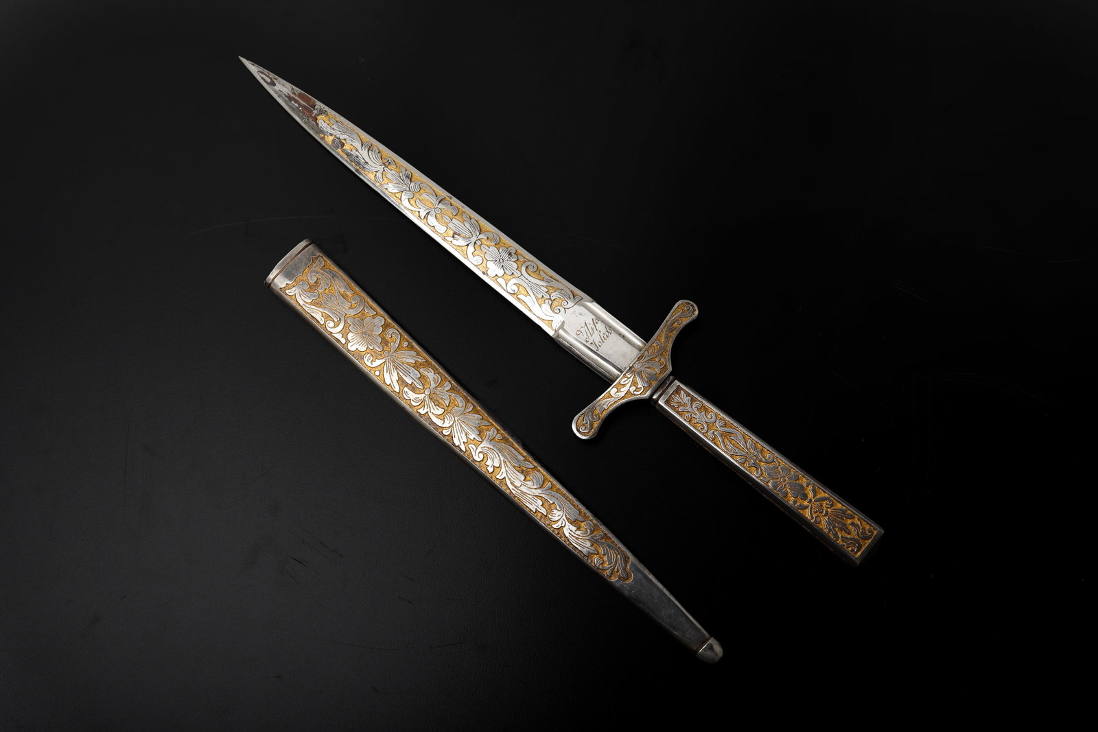 Spanish Toledo Gilt Floral Dagger, circa 1851: Spanish Toledo presentation dagger dated 1851, with a straight double edged steel blade and sharp reinforced point. The blade, guard, grip, and fitted metal sheath are decorated with silver tone and