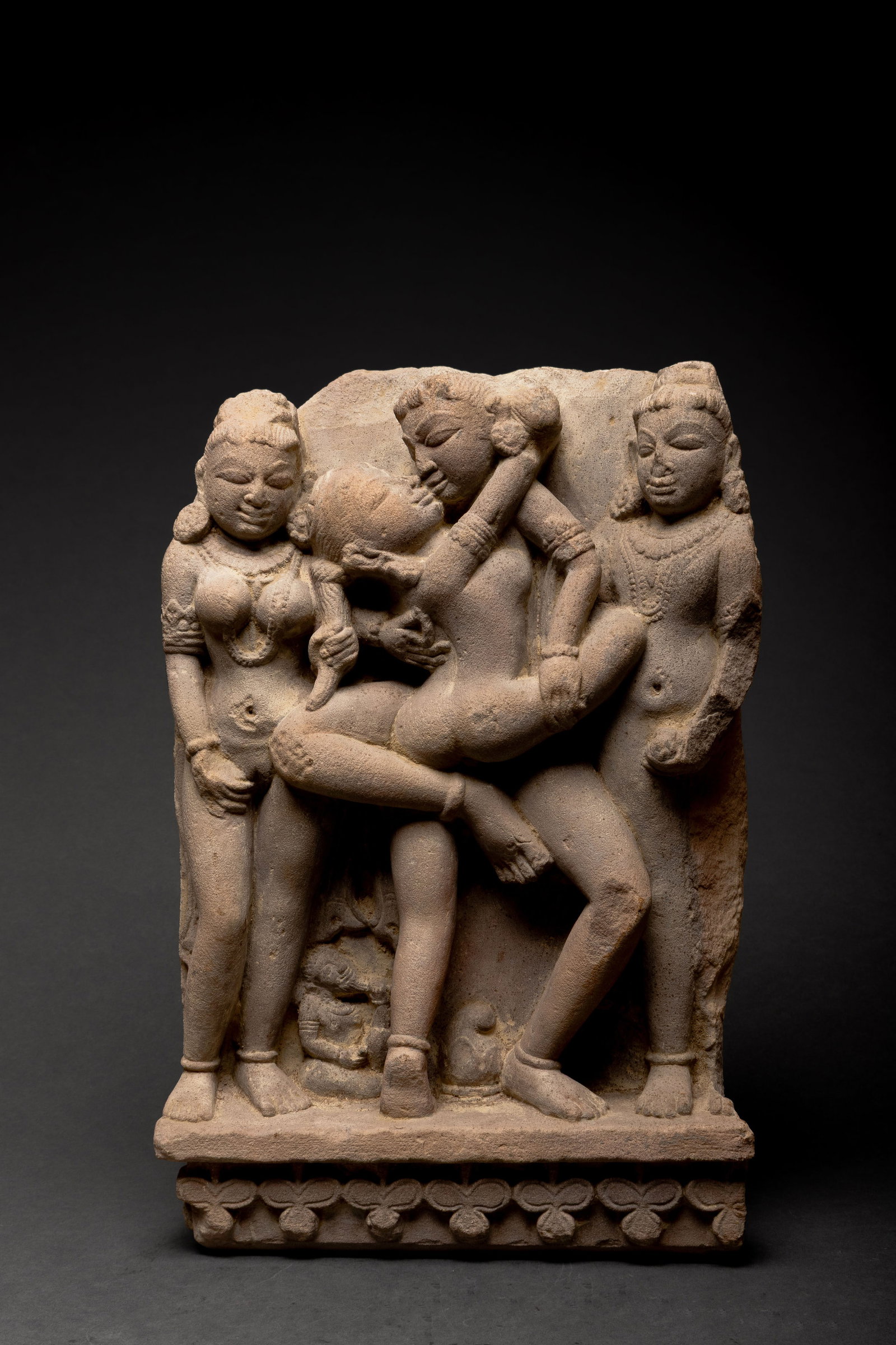Indian Carved Sandstone Maithuna Relief Panel, 16th - 17th C.: India, 16th to 17th century. A fantastic carved sandstone high relief panel depicting a maithuna, or erotic temple scene, with a central embracing couple attended by two standing female figures. The f