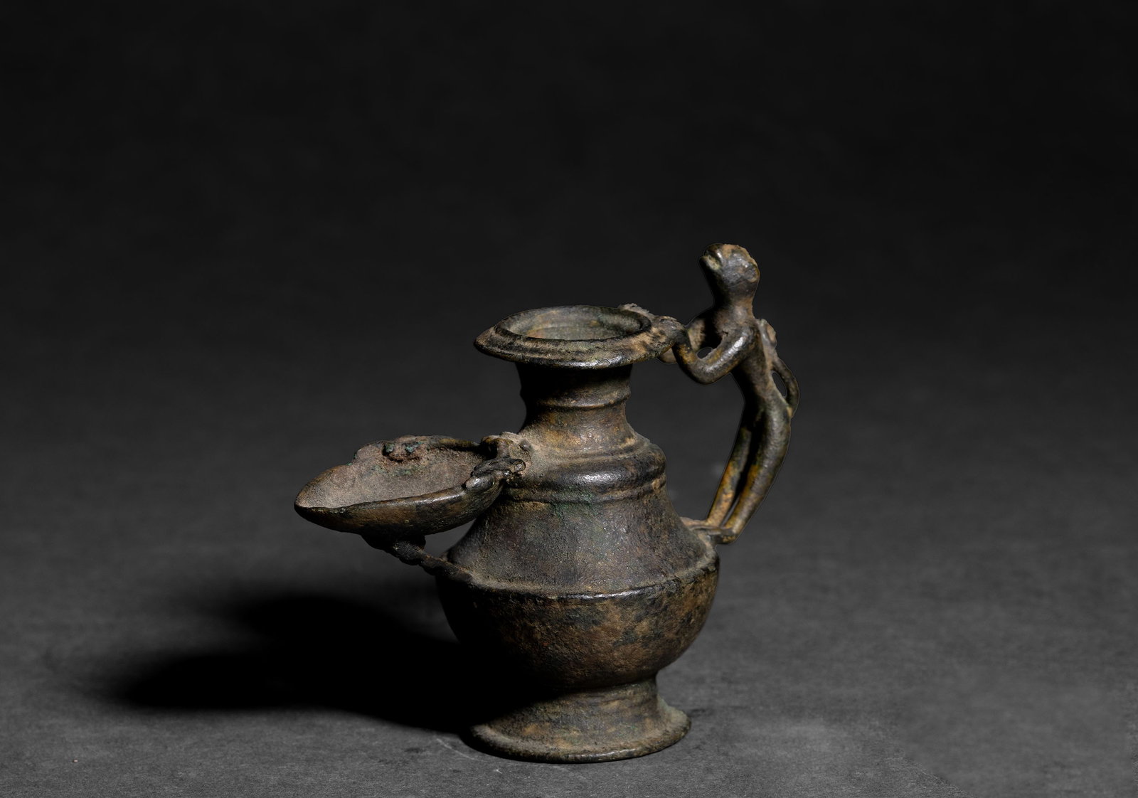 Tibetan Bronze Zoomorphic Oil Lamp with Monkey Handle, 18th C.: Tibetan, 18th century. Bronze zoomorphic oil lamp with rounded body, flared foot, raised neck, and cup form mouth. The vessel has a covered spout and a monkey form handle. Surface has dark aged