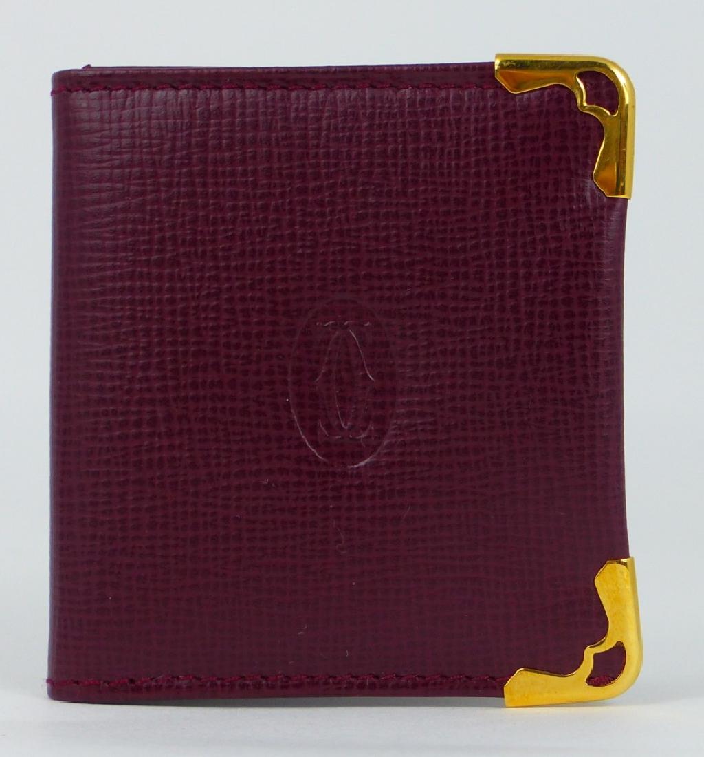 CARTIER PHOTO HOLDER w BOX: Cartier burgundy leather photo holder with gilt corner caps. Cartier medallion to center. Includes original box. Photo holder measures 2 5/8" (6.6cm) x 2 1/2" (6.3cm).