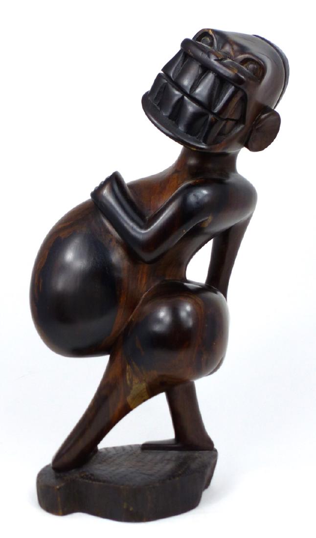 CARVED TRIBAL HARDWOOD FIGURE: Carved tribal hardwood figure with large belly and impressive smile. Measures 12 1/4" (31cm) height.