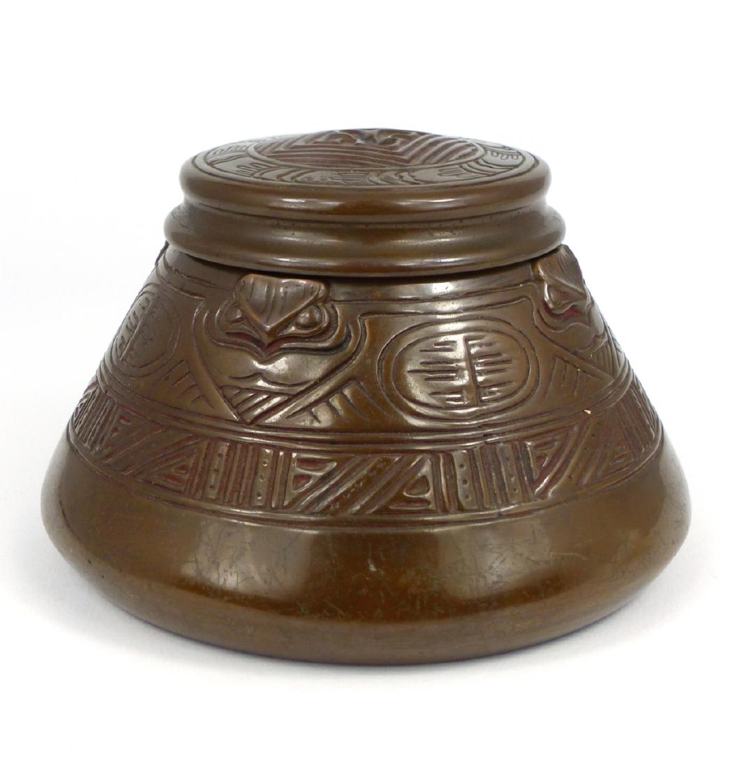 TIFFANY STUDIOS 'AMERICAN INDIAN' BRONZE INKWELL: Tiffany Studios bronze inkwell in the 'American Indian' pattern with glass ink cup. Marked to underside Tiffany Studios, New York and numbered 1183. Measures 5 1/2" (14cm) diameter.