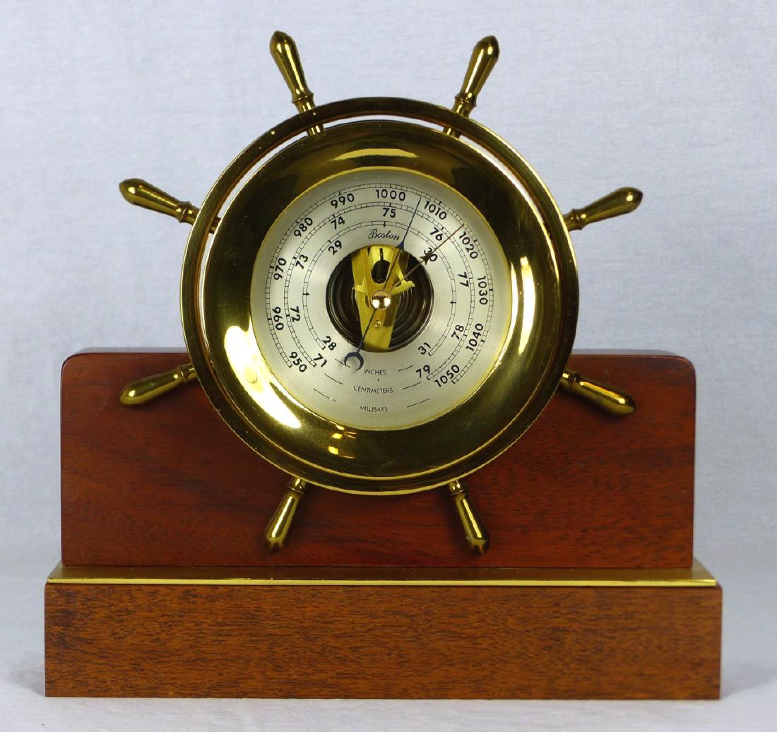 BOSTON BRASS SHIPS BAROMETER ON HELMSMAN BASE: Boston brass cased ship's wheel barometer, possibly Chelsea. Mounted on a Seth Thomas Helmsman base. Ship wheel measures approx 8 1/2" (21.5cm) diameter. Measures 10 3/4" (27.5cm) overall length.