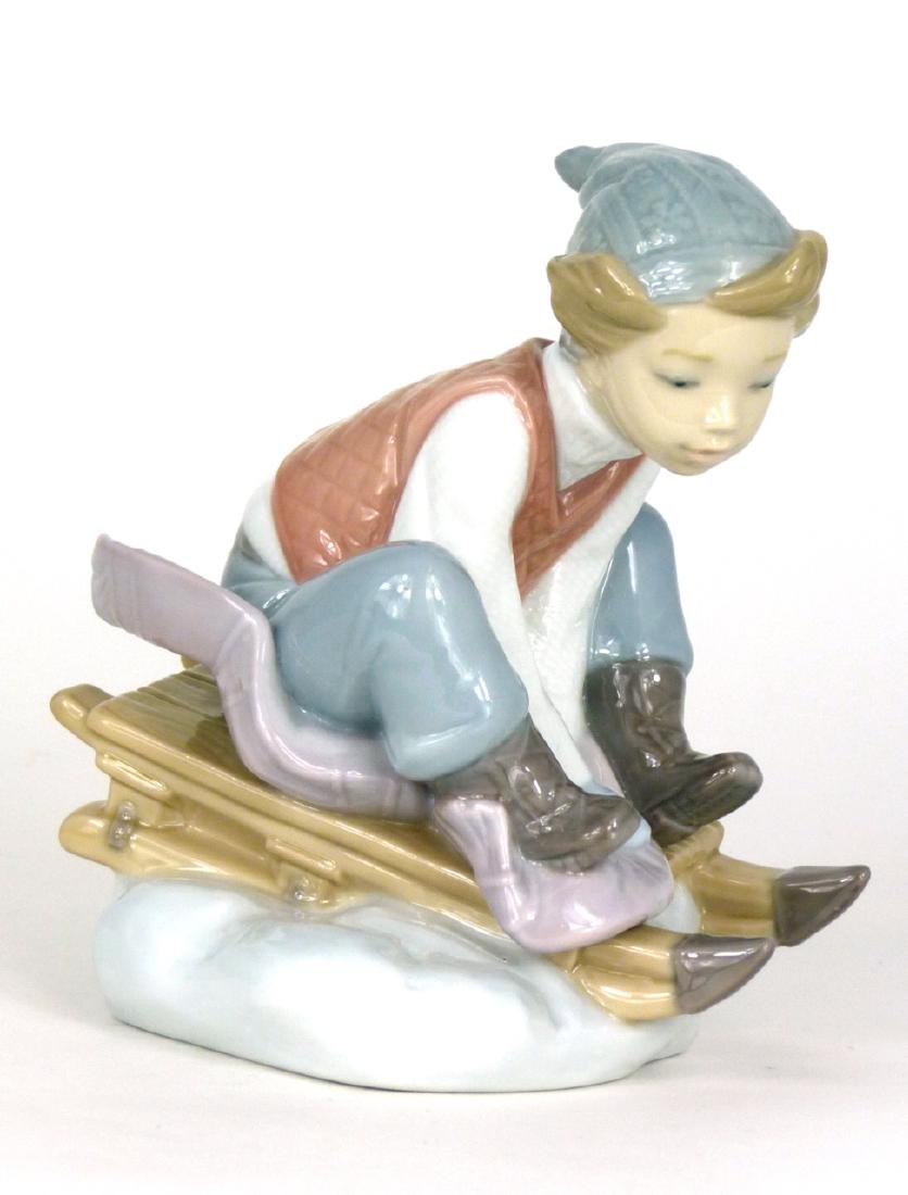 LLADRO 'LOOK OUT BELOW' PORCELAIN FIGURINE: Lladro porcelain figure depicting a boy on sled, #8264. Marked to underside. Measures 5" (12.7cm) height.