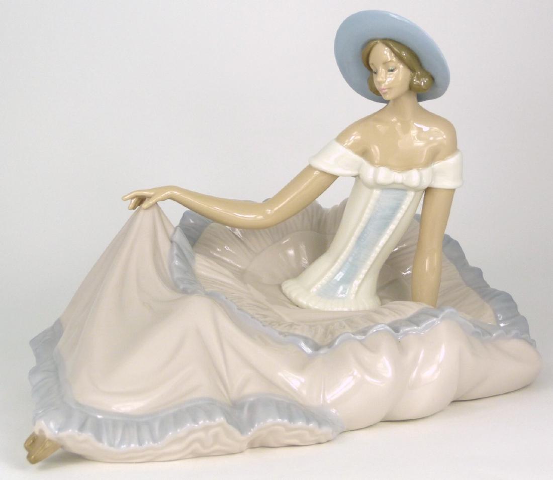 NAO LLADRO 'GRACE' PORCELAIN FIGURINE: Nao Lladro porcelain figure depicting a seated girl in large dress, #1265. Marked to underside. Measures 13 1/2" (34cm) length.
