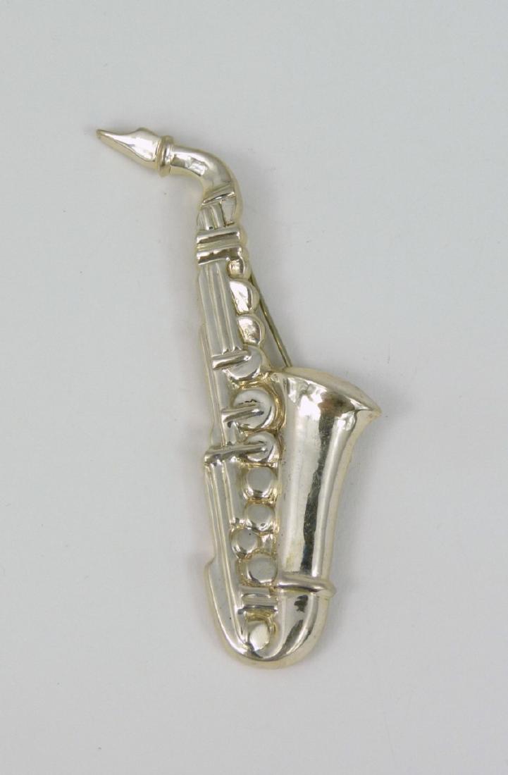 TIFFANY & CO STERLING SILVER SAXOPHONE BROOCH: Tiffany sterling silver pin in the form of a saxophone. Marked Tiffany & Co, Sterling to underside. Measures 3 3/8" (8.6cm) length.