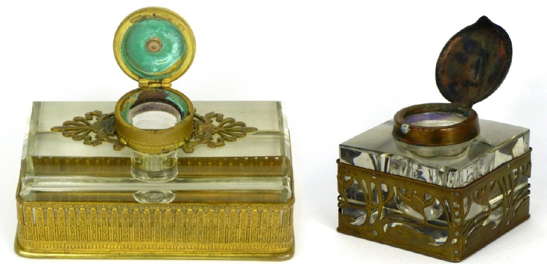 2pc BRASS MOUNTED GLASS INKWELLS: 2 brass mounted glass inkwells, One is Art Nouveau style with lilypad motif. Second is Classical style with pen holder. Largest measures 5 3/8" (13.7cm) length.