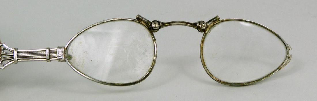 ANTIQUE STERLING SILVER LADY'S FOLDING EYEGLASSES: Antique sterling silver folding glasses on sterling chain. Marked Sterling to nosepiece and clasp. Chain measures 25" (63.5cm) length. Glasses measure 4 1/2" (11.3cm) opened.