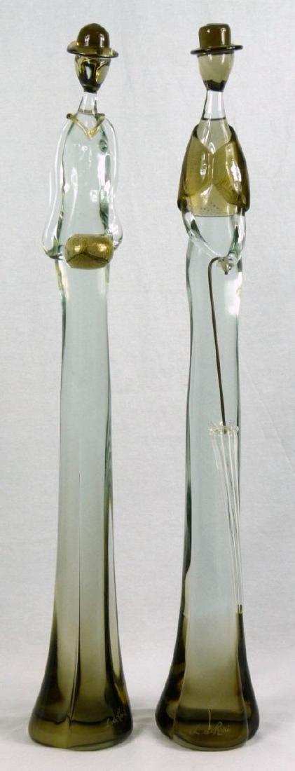 PR L. DE ROI VENETIAN ART GLASS FIGURAL SCULPTURES: Pair of Venetian art glass sculptures depicting standing figures with gold fleck accents. One figure holding removable umbrella. Each signed to side of base L. de Roi and measures 28 1/2" (72.3cm) hei