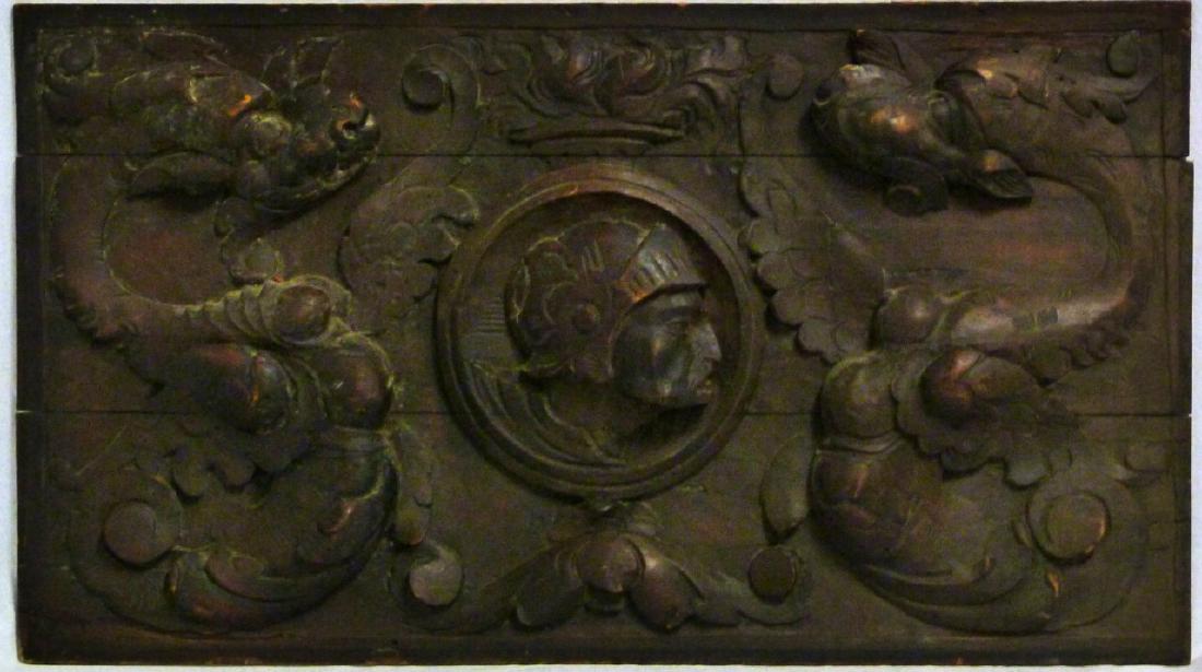 ITALIAN ANTIQUE RELIEF CARVED WOOD PLAQUE: 18th century Italian wood plaque carved in deep relief. Depicts two winged serpents with the head of a soldier to center. Believed to be from the captain's cabin of a merchant ship. Measures 26 1/2" (