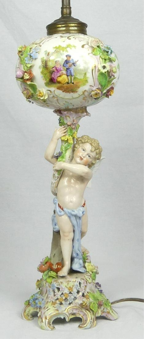 CARL THIEME FIGURAL PORCELAIN LAMP: Carl Thieme German porcelain lamp with cherub. Floral vignettes and applied flowers. Porcelain measures 15 3/4" (40cm) height. Overall 27" (68.5cm) height.