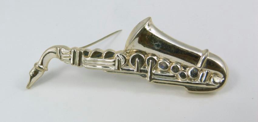 TIFFANY & CO STERLING SILVER SAXOPHONE BROOCH: Tiffany & Company sterling silver pin in the form of a saxophone. Marked Tiffany & Co, Sterling. Measures 3 1/4" (8.2cm) length. Total weight 19.2g.