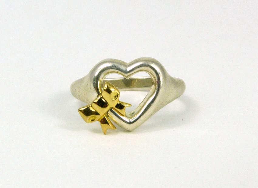 TIFFANY & CO STERLING SILVER & 18kt YG HEART RING: Tiffany & Company sterling silver heart with with 18kt yellow gold bow. Marked Tiffany & Co, 925, 750. Ring size 7.