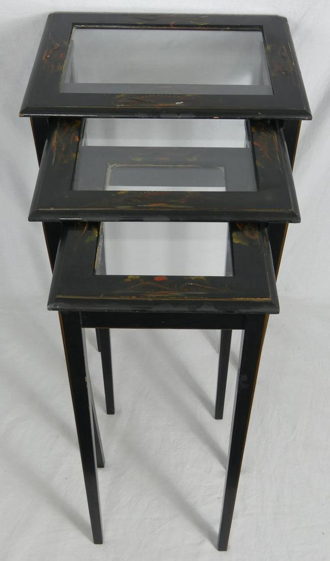 3pc JAPANESE BLACK LACQUER NESTING TABLES: 3 Japanese black lacquered interlocking nesting tables. Each with glass top surrounded by hand painted landscape scenes. Largest measures 14 1/2" x 11 1/4" x 22 1/4" height.