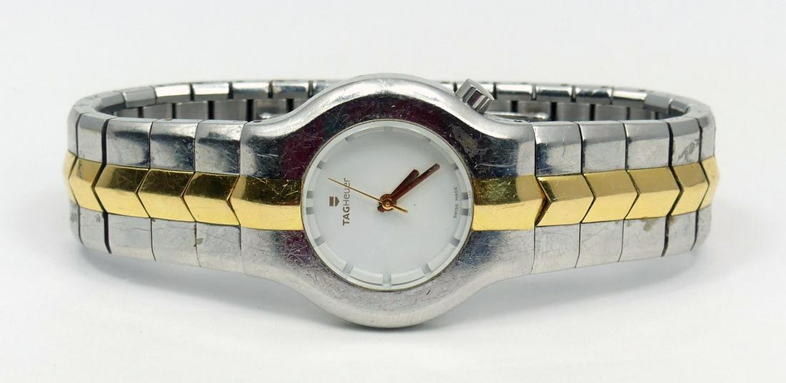 TAG HEUER STAINLESS & 18K GOLD LADIES WATCH: Tag Heuer stainless steel and 18k yellow gold ladies wristwatch. White dial with yellow gold hands. Signed to face, case and band. Push lock concealed deployment clasp. Case measures 29mm. Inner circu