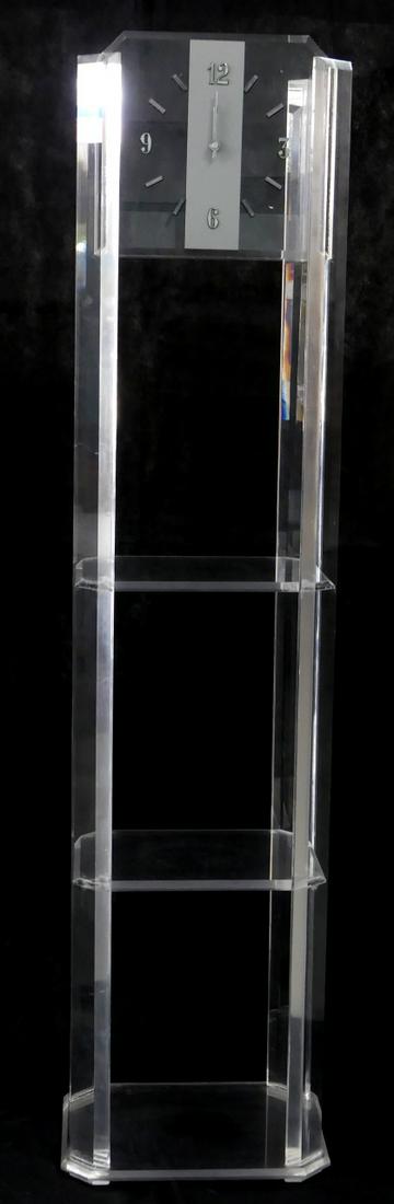 MID-CENTURY LUCITE FLOOR CLOCK: Mid-century lucite floor clock with quartz movement. Chrome numbers and hands to face with three shelves below. Measures 61 1/4" (155.5cm) x 14" (35.5cm) width x 11 1/4" (28.5cm) depth.