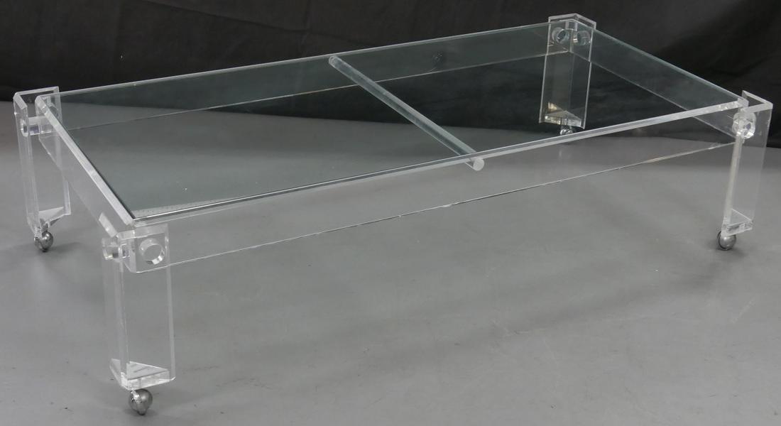 LUCITE & GLASS COFFEE TABLE: Mid-century lucite coffee table on four chrome wheels with glass top. Measures 60" (152.4cm) x 30" (76.2cm) x 15" (38cm) height.
