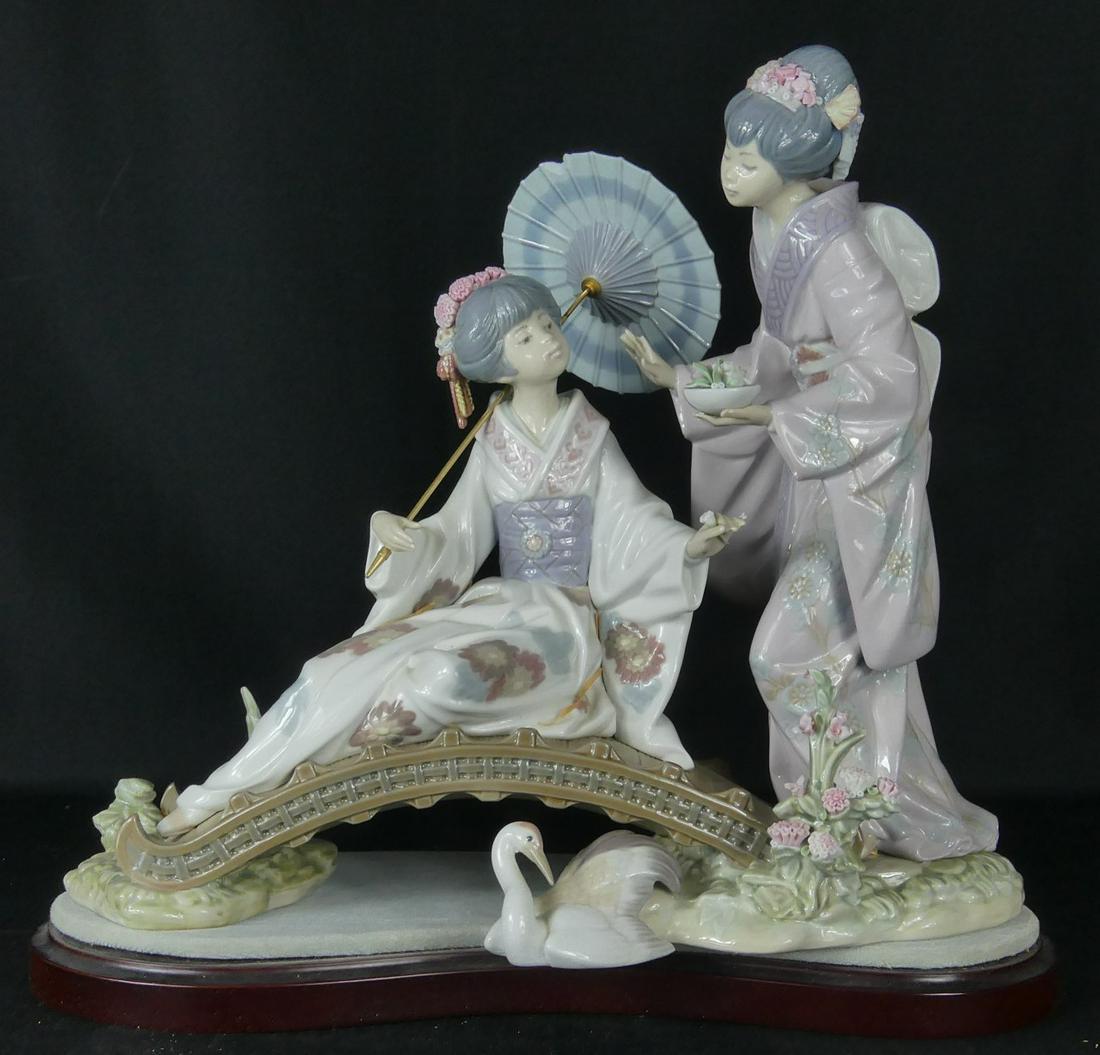 LLADRO SPRINGTIME IN JAPAN PORCELAIN FIGURE w BOX: Lladro porcelain figure titled 'Springtime In Japan'. Depicts two Geisha girls on a bridge with crane. Marked to underside. Measures 13" length x 11 3/4" height. Includes original box.