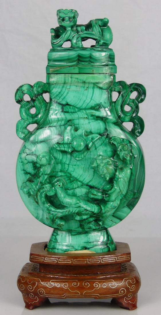 CHINESE CARVED MALACHITE COVERED URN: Chinese carved malachite covered urn. Qilin carved in relief to body. Having twin pierced handles to neck and foo lion to lid. Measures 6" height + 1 3/8" fitted wooden base.