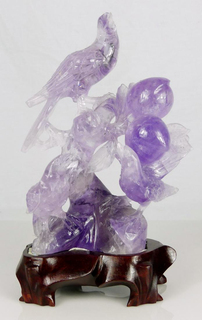 CHINESE CARVED AMETHYST BIRD GROUP: Chinese carved amethyst sculpture depicting three birds perched on a branch with peaches and leaves. Measures 6" height + 1 1/4" fitted wooden base.