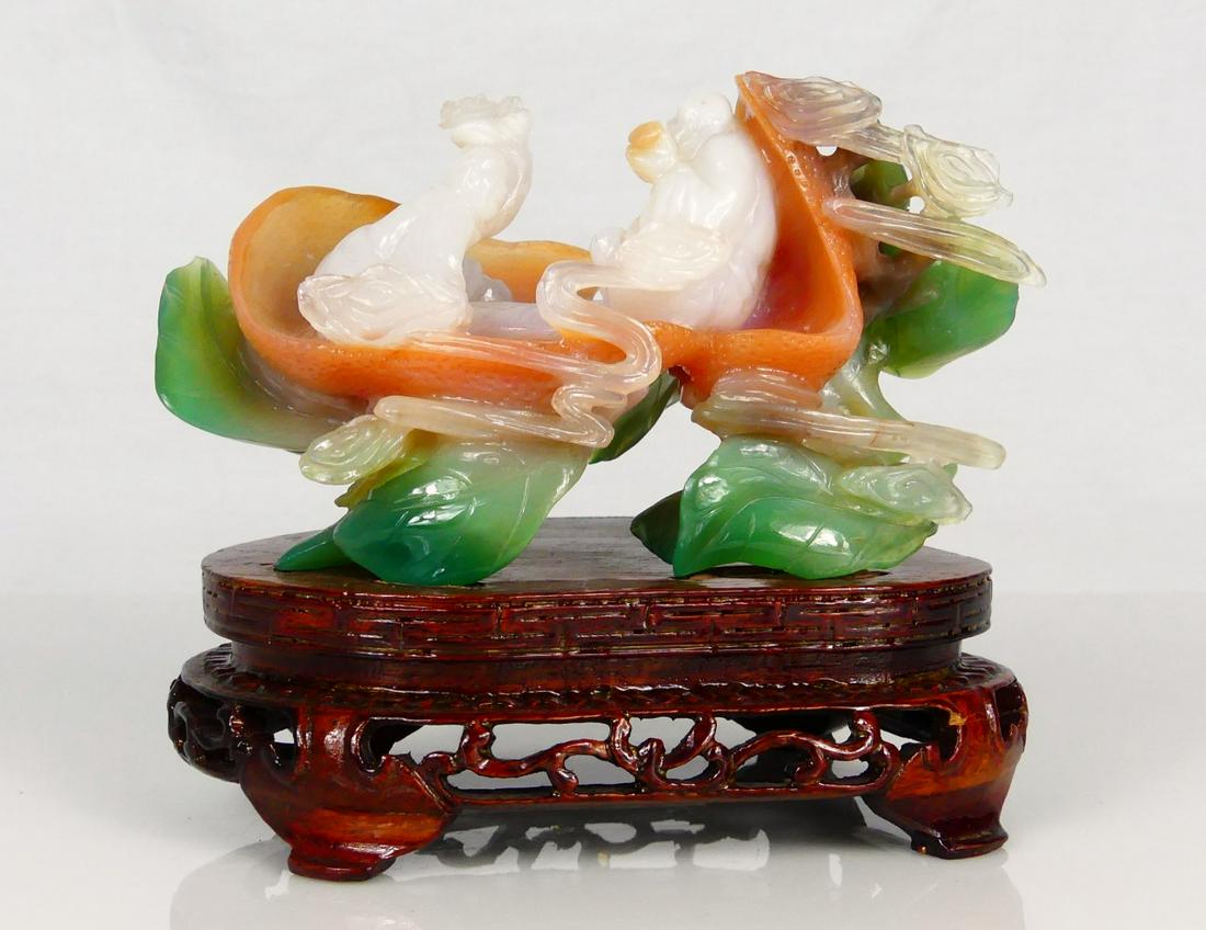 CHINESE CARVED MULTI-COLOR JADE SCULPTURE: Chinese carved multi-color jade sculpture depicting two white figures seated upon a peach-colored lotus leaf raised on several green leaves. Jade measures 4 1/2" length x 2 1/2" height + 1 3/8" base.