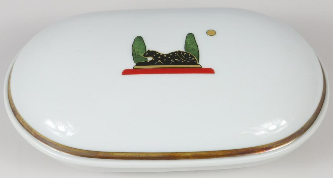 CARTIER 'LA MAISON DE CARTIER' PORCELAIN BOX: Cartier Limoges oval covered porcelain box in the 'La Maison De Cartier' pattern. Black panther decoration to cover. Marked to underside. Measures 6 3/4" length. Includes certificate of authenticity.
